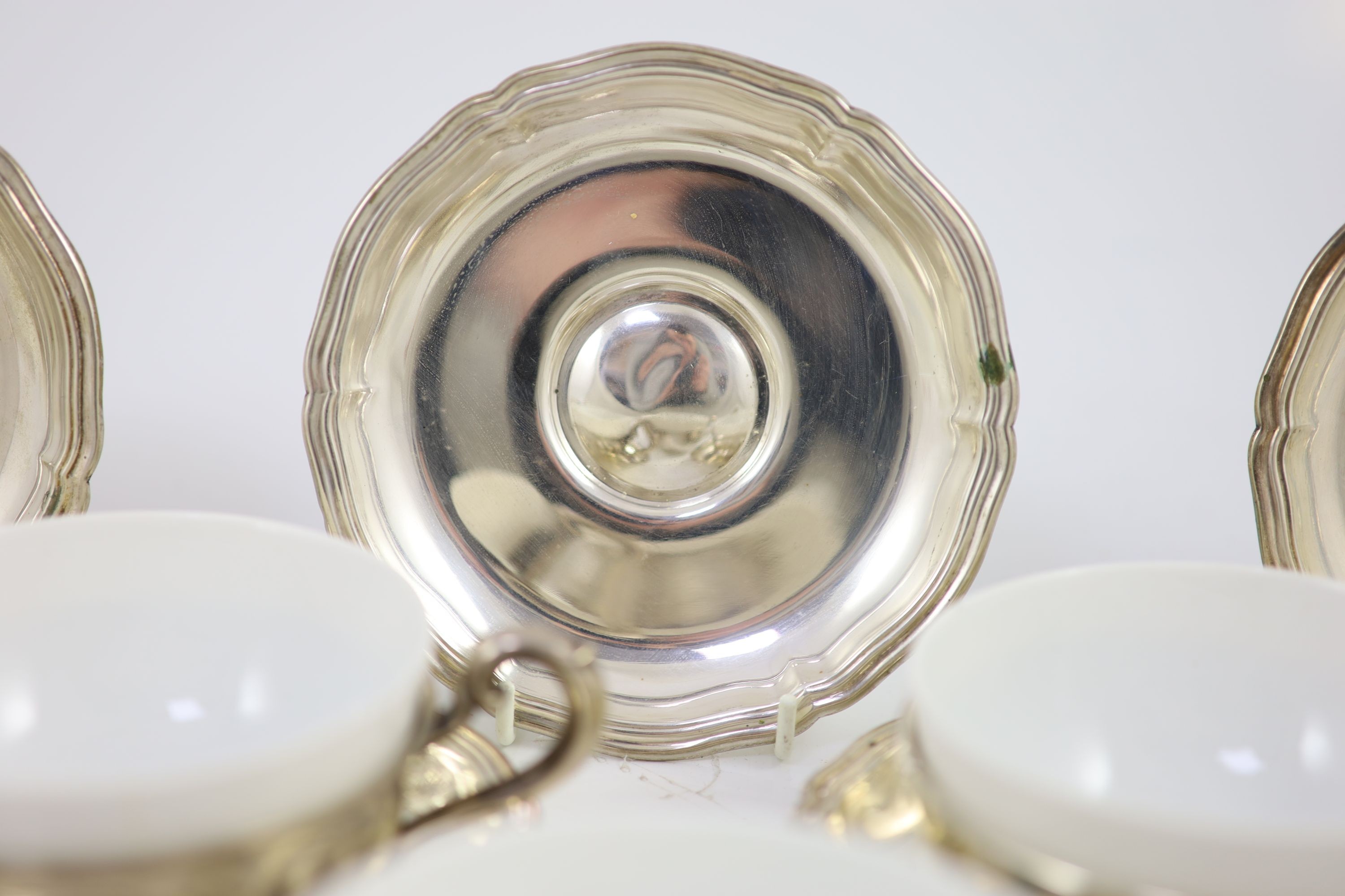 A set of eight German 800 standard silver cups and saucers, by Adolf Kander, with white porcelain liners